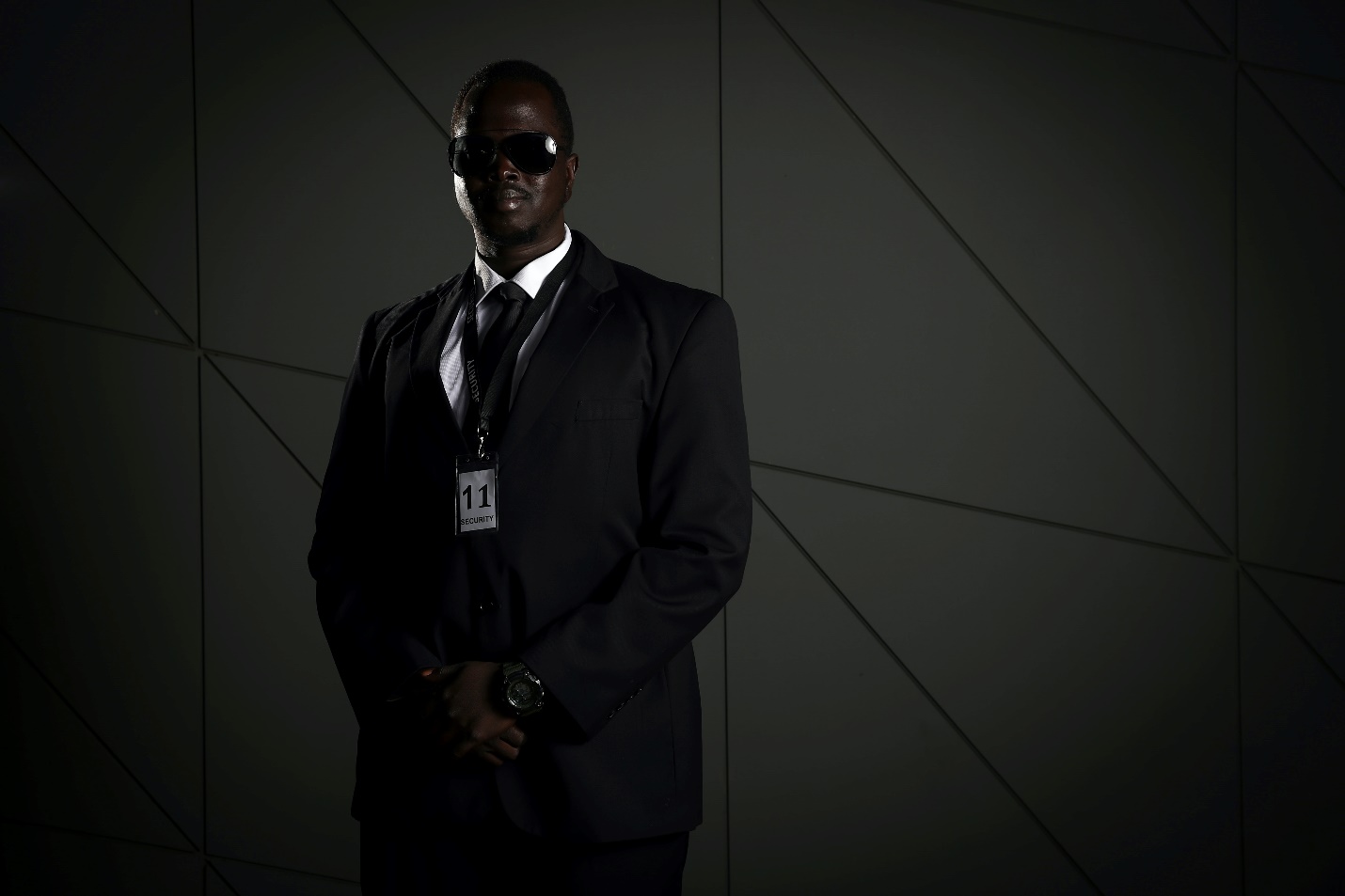 Security guard in a suit standing against a wall