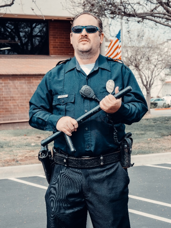 A security service standing alert on the street outside a bank